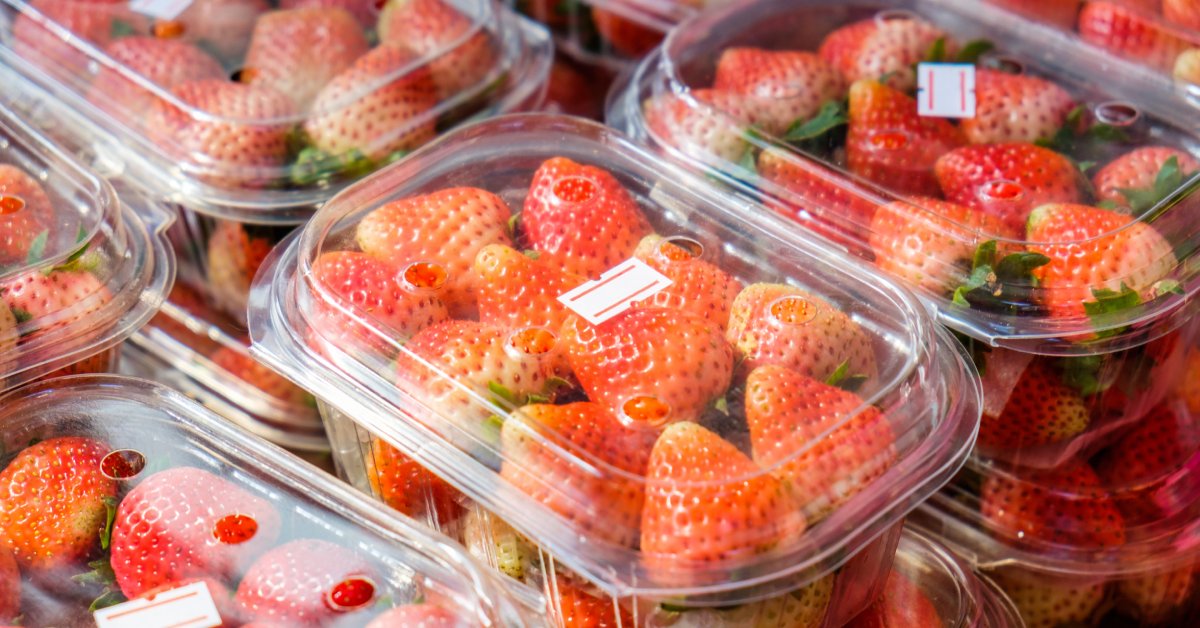 Closeup of several stacks of plastic produce packaging containers filled with strawberries with price labels.